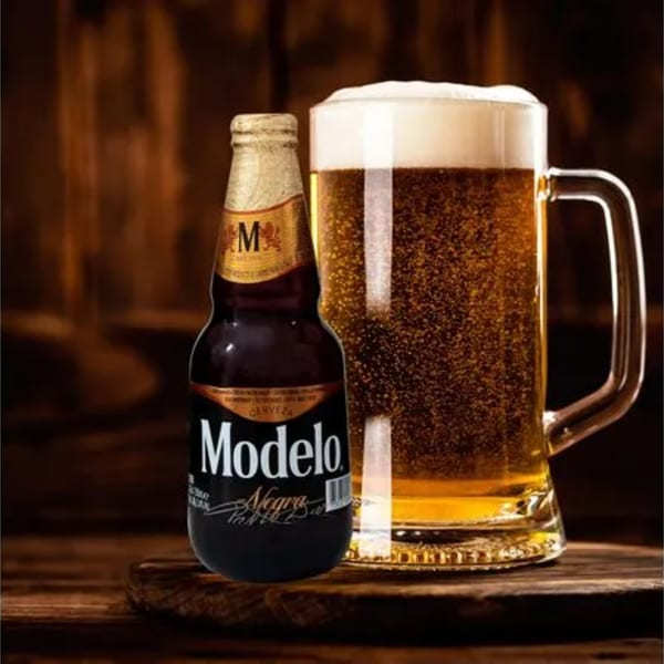 A Modelo Negra beer bottle next to a frosty mug of golden beer with a foamy head.