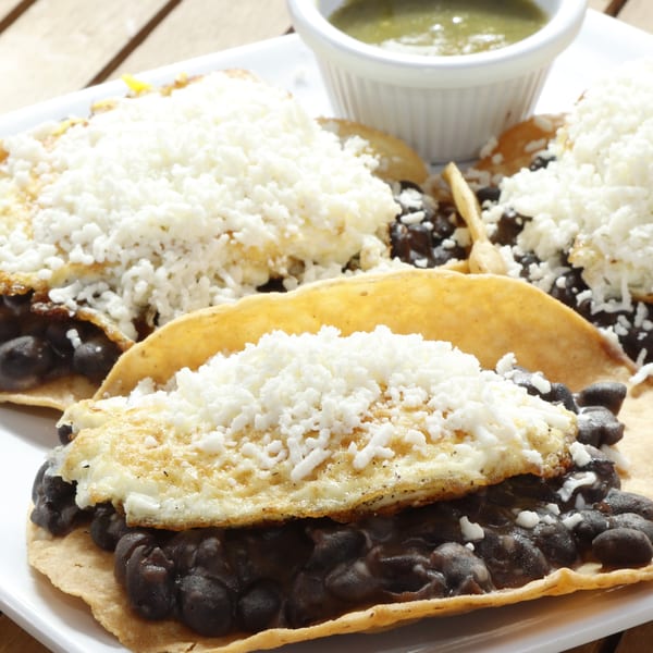 Le Fernández Café's huevos rancheros with black beans, fried eggs, and crumbled cheese, with green salsa.