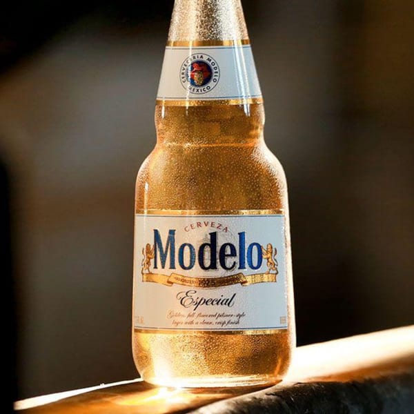 A cold, condensation-covered bottle of Modelo Especial beer stands on a wooden surface.